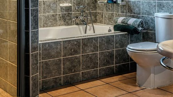 Moderne bad med badekar og mørke grå fliser